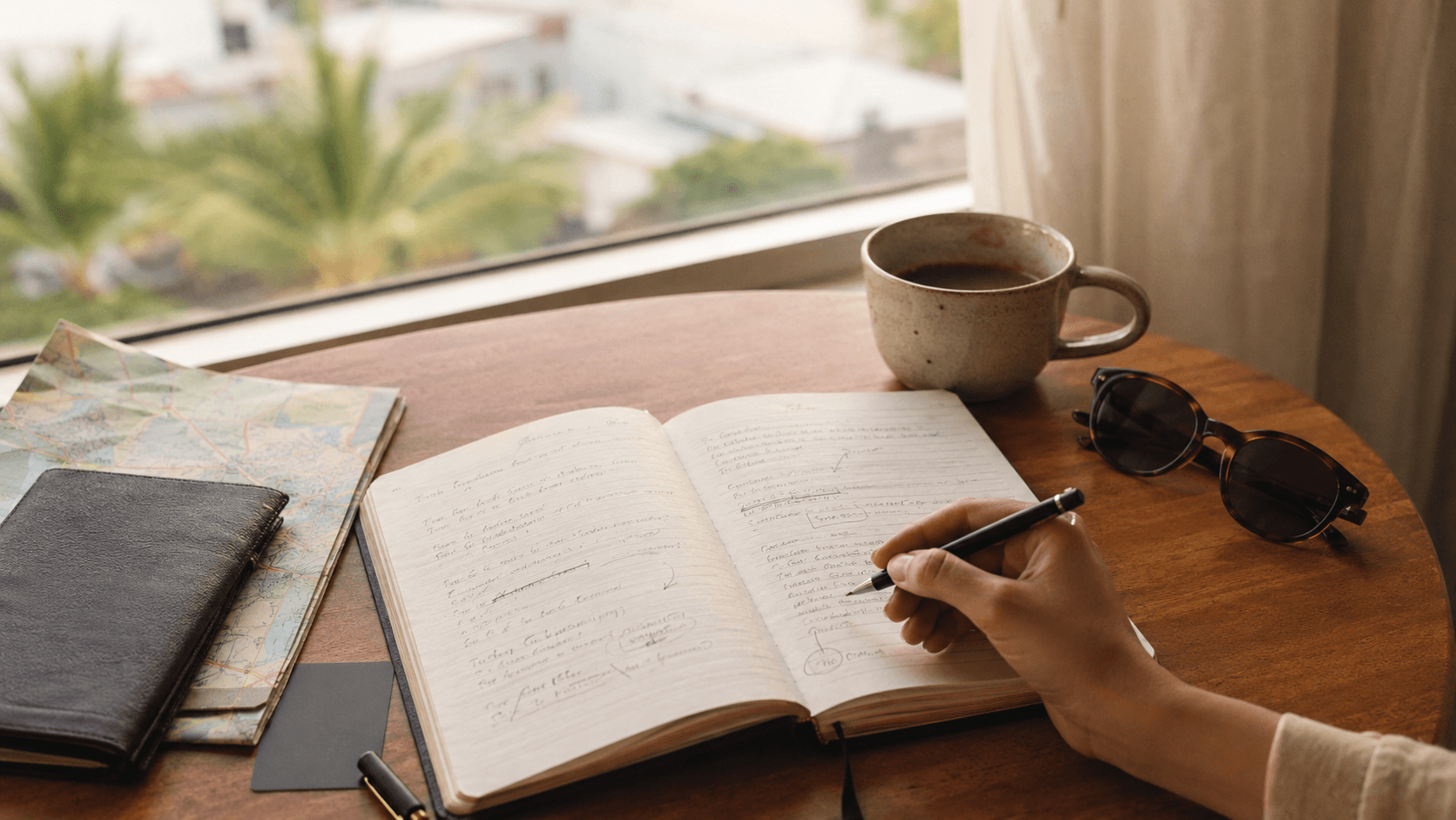 Notebook and coffee on a table, travel setting, no visible face